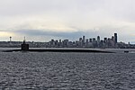 Sideview of submarine on surface, with the outline of a city in the background.