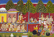 Seated man talking to many other men, with trees and musicians in the background