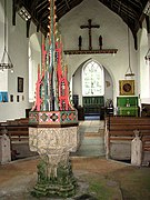 The tall ornate font cover of the font dates from the 20th century and originates from the parish church in Buxton, Norfolk.