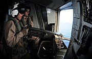 CH-53Eのキャビンに搭載されたGAU-15/Aを射撃するアメリカ海兵隊兵士。弾着を見ながら照準修正を行っている。