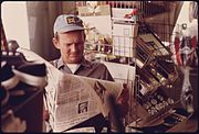 "HADACOL," een klusjesman in Robertstown, Georgia, leest tussen de bedrijven door z'n krantje. Juli 1975