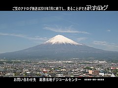 模仿日本地面模拟电视停播前一段时间的电视画面。右上角有“アナログ”（模拟）字样；屏幕上方和下放的字幕提示观众在2011年7月之后，观众将无法收看模拟电视节目，观众可致电总务省了解详情。