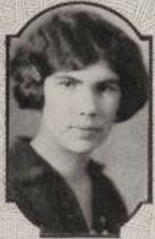 A young white woman with dark hair in a wavy bobbed style, wearing a dark collared blouse