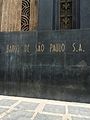 Grafia em mármore na parede lateral esquerda do edifício, que o nomeia como "Banco de São Paulo".