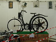 Flix Millet's 1897 motorcycle, showing the common ancestry of motorized bicycles and motorcycles. Note the rotary engine built into the back wheel.