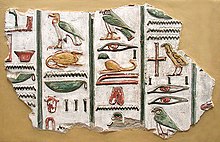 A stone fragment with brightly-painted colors and raised-relief images of Egyptian hieroglyphs, written in vertical columns, set against a beige background