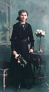 Jugendweihe is a German coming of age ceremony. Photograph from early 20th century. Otto Martin junge Dame im schwarzen Kleid mit Blumen.jpg