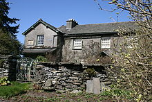 Ein Haus in mittlerer Entfernung, eine Gartenmauer und ein Tor