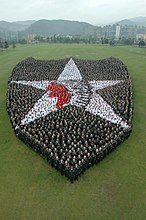 Aproximadamente cinco mil soldados da 2.ª Divisão de Infantaria criam uma versão humana do distintivo Indianhead patch da divisão no Indianhead Stage Field em Camp Casey, Coréia, 2009