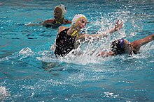 woman in water lunging for the ball