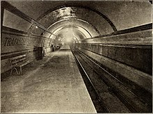 Круговой туннель с платформой слева и путями справа. Стена платформы выложена полосами с надписью TRAFALGAR SQUARE, выделенной цветной плиткой.