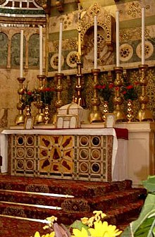 A pre-1969 Roman-Rite high altar decorated with reredos and set on a three-step platform, below which the Prayers at the Foot of the Altar are said. Leaning against the tabernacle and two of the candlesticks are altar cards, to remind the celebrant of the words when he is away from the missal. Unchurch.jpg