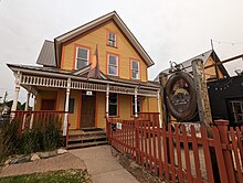 A photo of an aging home with a business sign