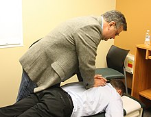 A chiropractor performs an adjustment on a patient. Chiropractic spinal adjustment.jpg