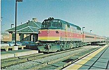 A train with a diesel locomotive at a suburban railway station