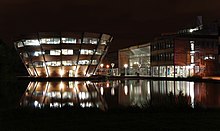 Jubilee Campus in 2012. On the left is the Sir Harry and Lady Djanogly Learning Resource Centre, a library which has the form of an inverted cone. Jubilee Campus MMB Z7 Djanogly LRC and The Exchange.jpg
