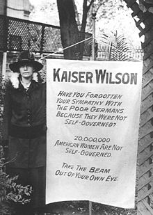Suffragist with banner, Washington DC, 1918 Suffragette banner carried in picket of the White House.jpg
