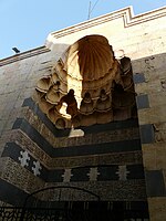 The entrance portal of the madrasa complex, composed of different coloured stone (ablaq), Arabic inscriptions, and a muqarnas canopy.