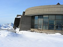 雪景色の中に建つガラス窓のある外壁が丸い建物。