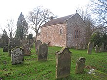 colour photograph of a stone church building in a graveyard, taken in 2010