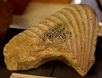 Siliceous limestone fragment of a statue with late form Aten cartouches on the draped right shoulder. Amarna, Egypt. New Kingdom, late 18th Dynasty. The Petrie Museum of Egyptian Archaeology, London