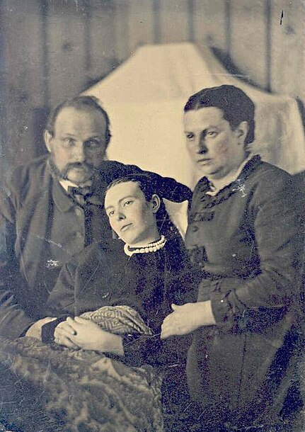 File:Victorian era post-mortem family portrait of parents with their deceased daughter.jpg