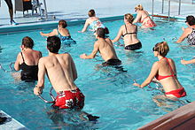 Группа людей в купальных костюмах на металлических рамах в мелком бассейне