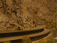 Двухуровневая автострада, огибающая повороты каньона, с заметной осенней листвой.
