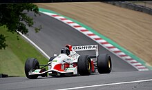 Photo d'une monoplace de Formule 1 blanche et rouge, vue de trois-quarts, dans son ensemble, roulant sur un circuit.