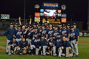 A group of men wearing navy blue baseball jerseys and caps and gray pants