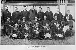 A group of 19 men arranged in three rows, many of them in naval uniforms