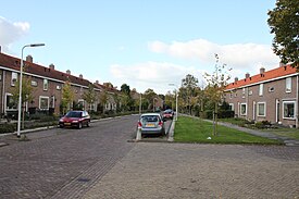 Een straat in Tollebeek. Oorspronkelijk was de rijbaan smaller en was er aan beide zijden een brede groenstrook. Toen het autobezit later toenam is een deel van de groenstroken verwijderd ten behoeve van parkeerplaatsen.