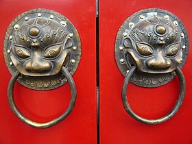 A traditional red Chinese door with Imperial guardian lion knocker
