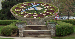 A large clock with flowers on the face that reads "Kentucky" and has an outline of the state in the middle