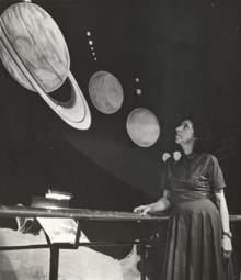 White woman standing, looking up at an astronomy exhibit.