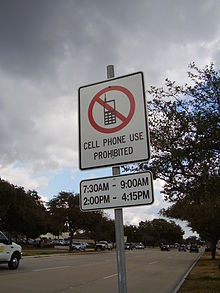A sign along Bellaire Boulevard in Southside Place, Texas (Greater Houston) states that using mobile phones while driving is prohibited from 7:30 am to 9:30 am and from 2:00 pm to 4:15 pm. NocellphonesSouthsidePlaceTX.JPG