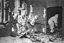 Trois soldats en uniforme blanc entrent dans les ruines d'un bâtiment en briques