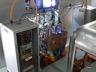 Two ion sources at the center with two high-voltage electronics cabinets next to them[10]