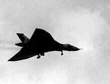 A delta-winged aircraft silhouetted against the sky. It has its landing wheels down.