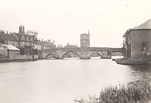 Photograph of a bridge over a river, with a rectangular building in the centre