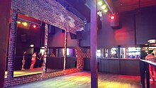 Photograph of the interior of a room with exposed brick and mirrors on the walls