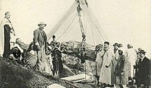 Carte postale ancienne représentant un groupe de personnes autour d'une installation destinée à faire sortir un sarcophage en forme de femme d'un puits funéraire.