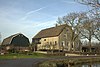 Forse boerderij onder hoog, rieten zadeldak met wolfeind aan de voorzijde. Gepleisterde voorgevel met staafankers. Hooggelegen vloedkamers; voordeur met stoep