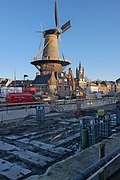 Photographie en couleurs d'un moulin à vent entouré d'un paysage urbain en travaux.