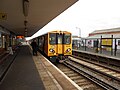 The guard waits to signal the departure of a Liverpool-bound train.