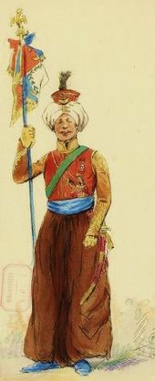 Soldat à pied, de face, coiffé d'un turban et vêtu d'habits orientaux et colorés, tenant de sa main droite un drapeau aux couleurs de la France.