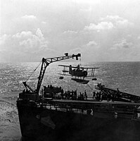 Jeřáb nakládá letoun na palubu lodi USS Philadelphia, foto: Horace Bristol.