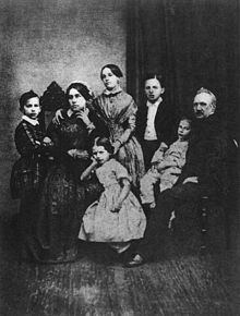 A family portrait, with the mother on the left and the father on the right surrounded by four children.
