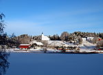 Foto einer Ortschaft in verschneiter Landschaft mit einer Kirche auf einer Anhöhe