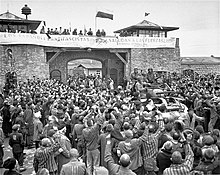 A US Army tank is surrounded by concentration camp survivors